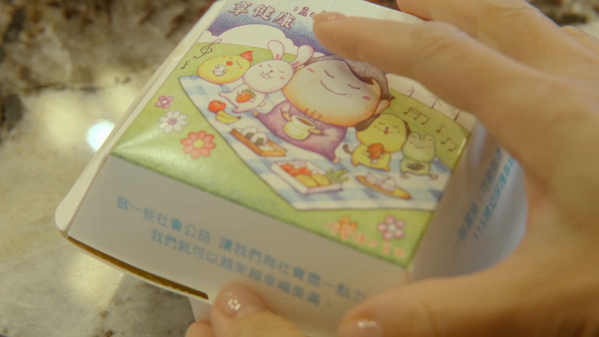 絵の描かれた朝食の紙箱を開ける手元