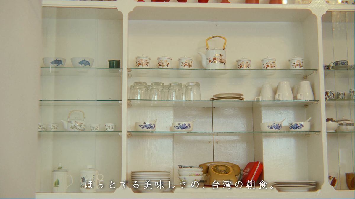 白い棚に並ぶ茶器とダイヤル式の電話