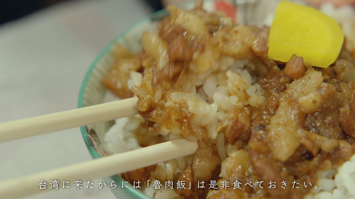 たくあんをのせた魯肉飯に箸を入れる