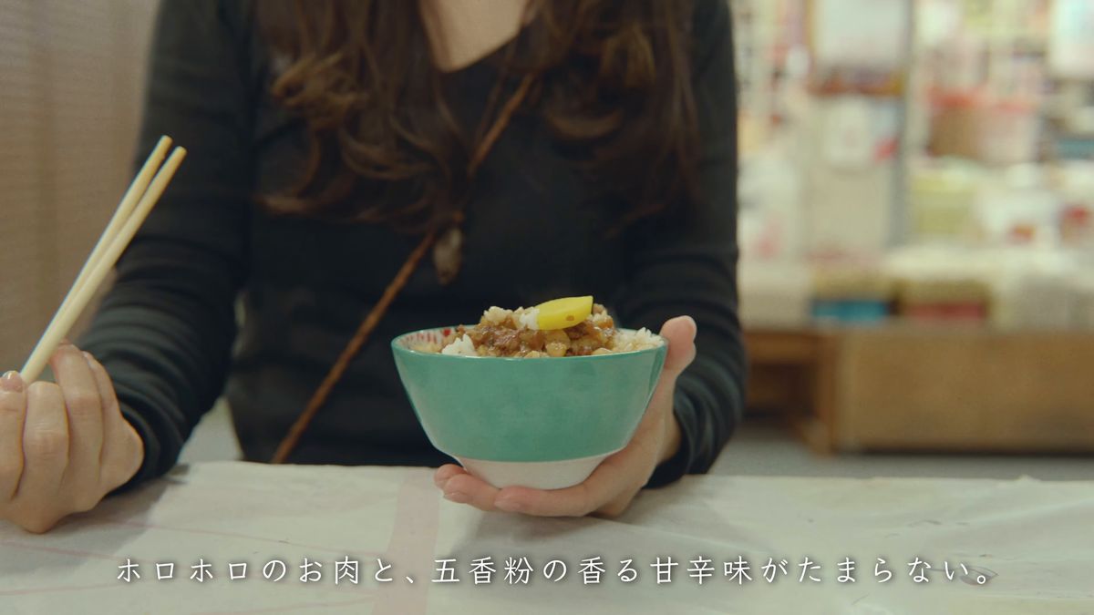 食堂の席で魯肉飯の器を持つ
