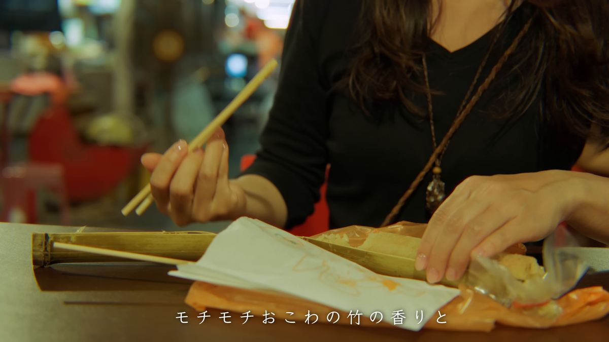 箸で竹筒飯を食べる