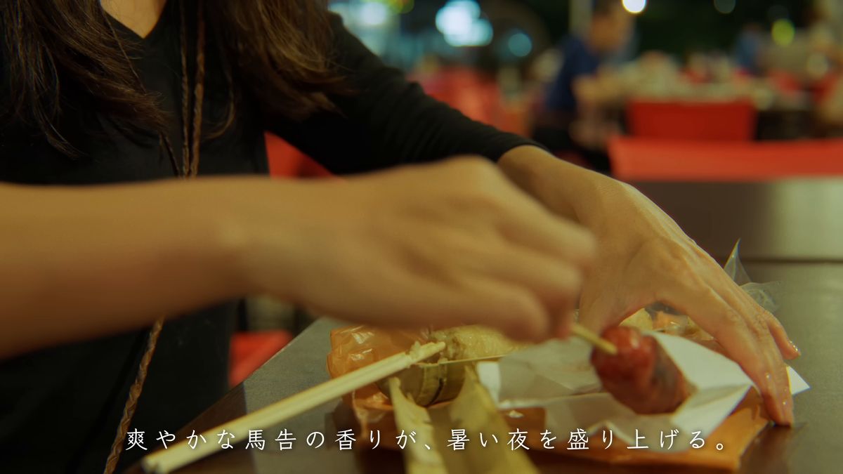 ソーセージの串と竹筒飯に手を添える