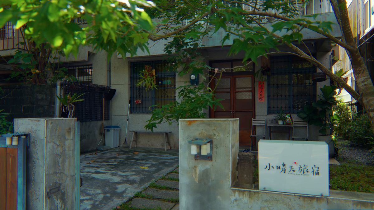 門柱の向こうに立つ宿の白い看板