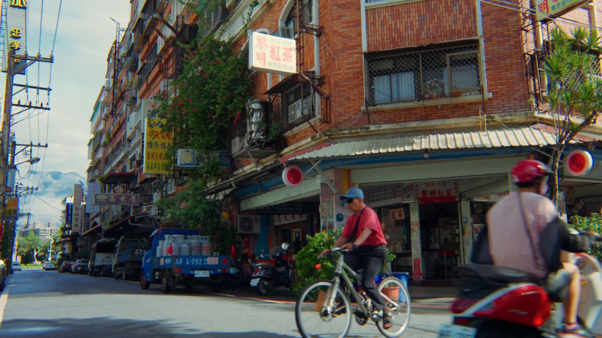 赤レンガの角に建つ黎明紅茶と、通りを行く自転車やバイク