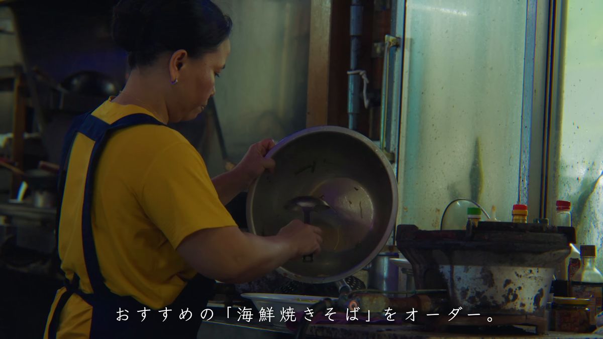 厨房で大きな鍋を手にする店の人