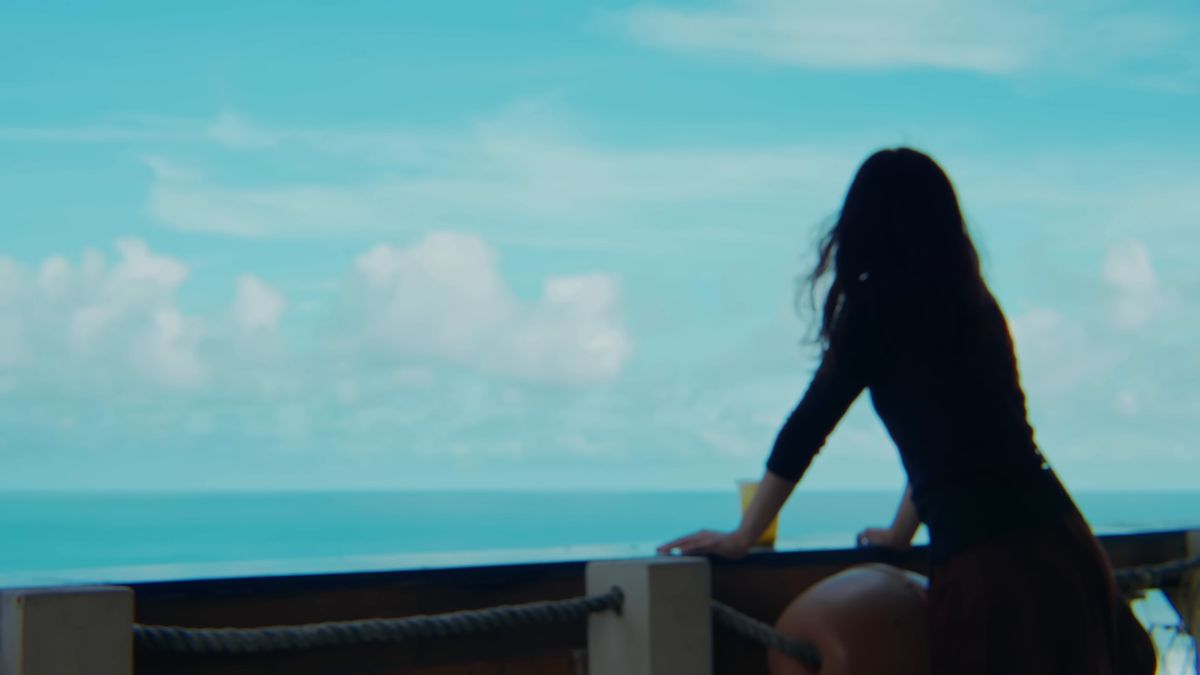 テラスの柵にもたれて海を眺める後ろ姿