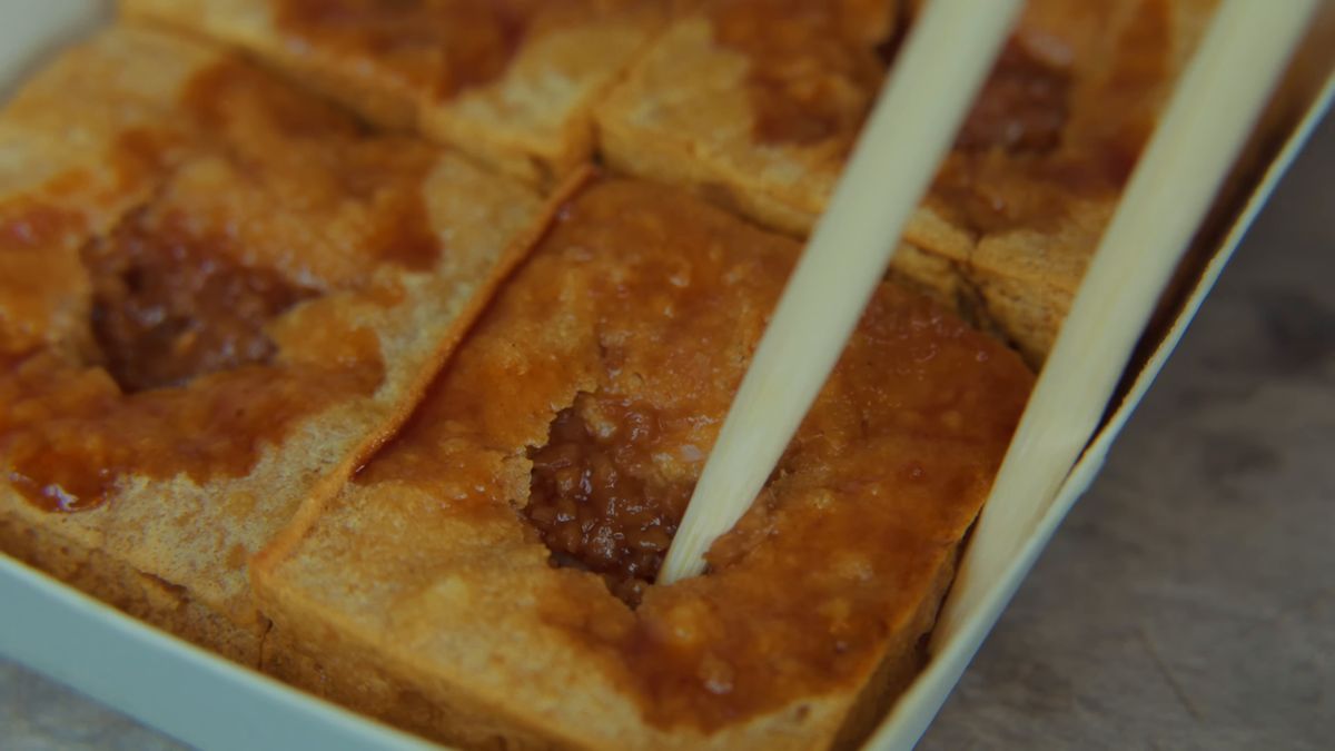 タレのしみた臭豆腐を箸で割る