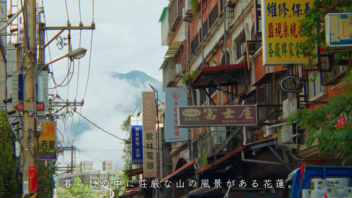 看板の並ぶ通りと、雲をまとった山