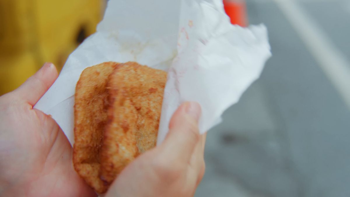 紙に包まれた炸蛋蔥油餅を手に