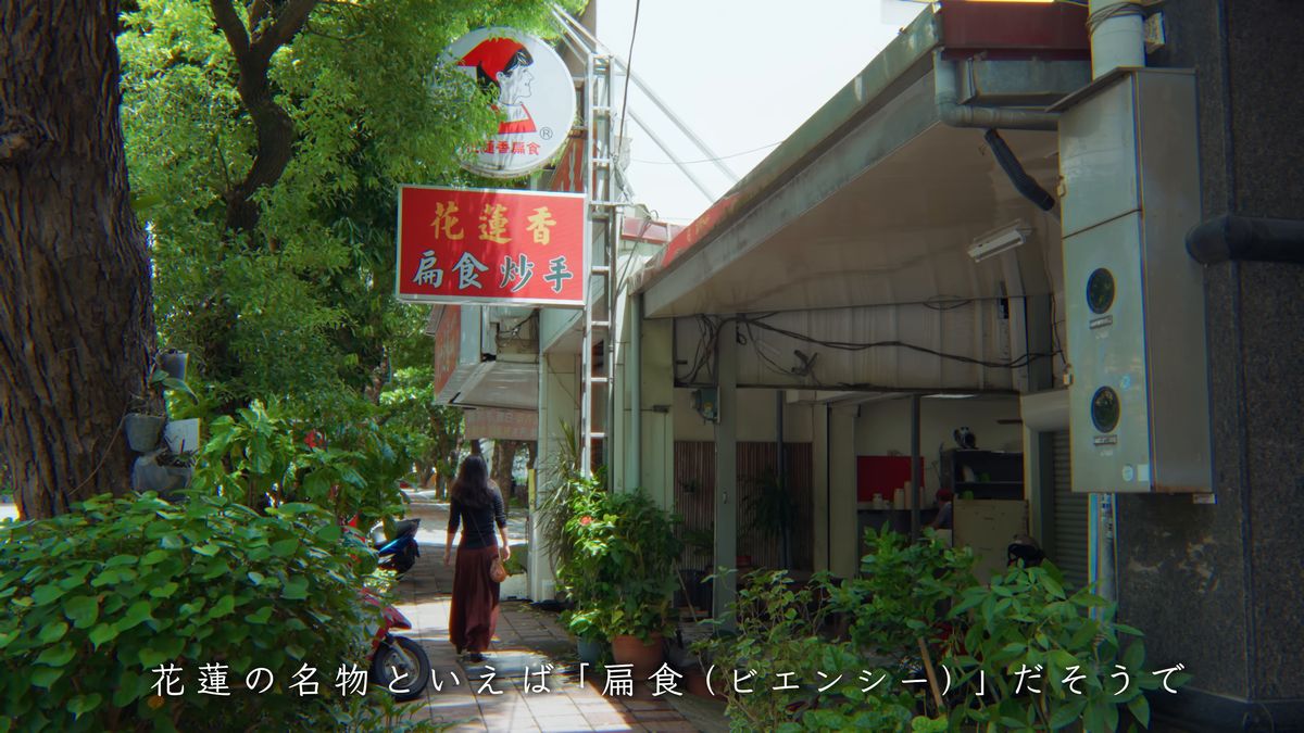 木々の茂る通りの扁食店に向かう後ろ姿