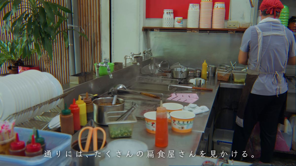 調味料の容器が並ぶ調理台と、店の人の後ろ姿