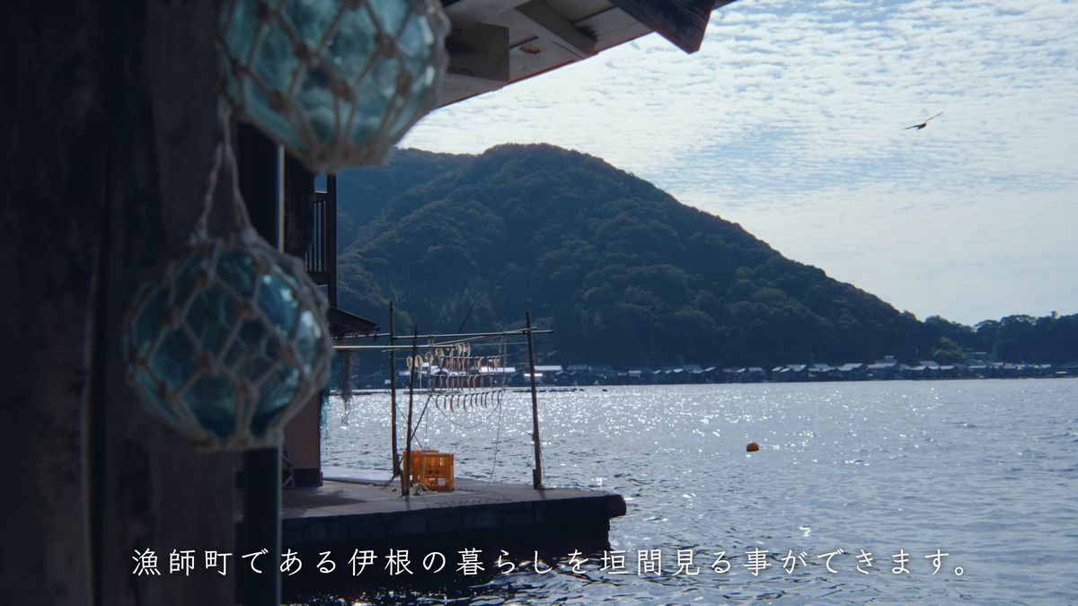 浮き玉越しに見る、光る海と対岸の山