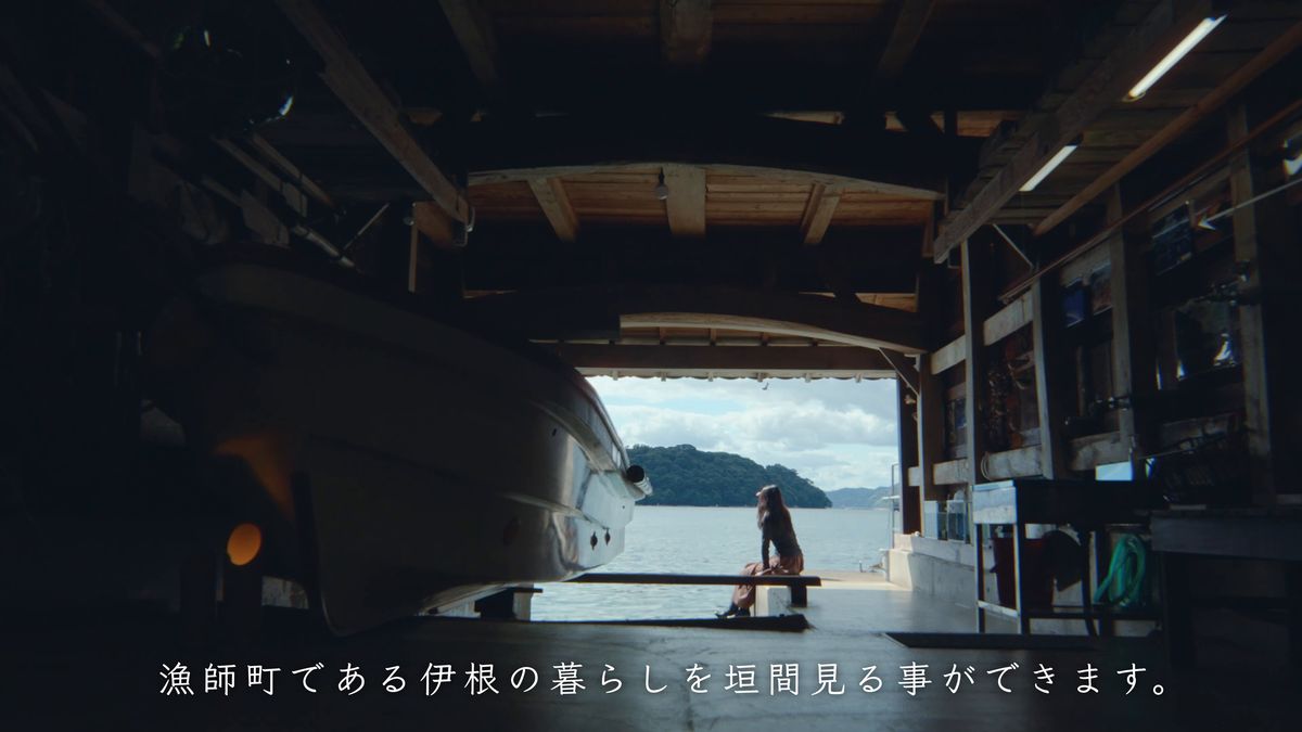 舟屋の中、船の脇のベンチに座って海を眺める後ろ姿