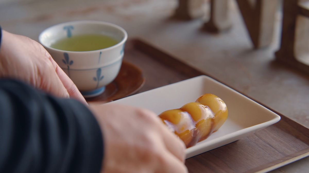 緑茶の盆の横に、みたらし団子の皿を置く手元