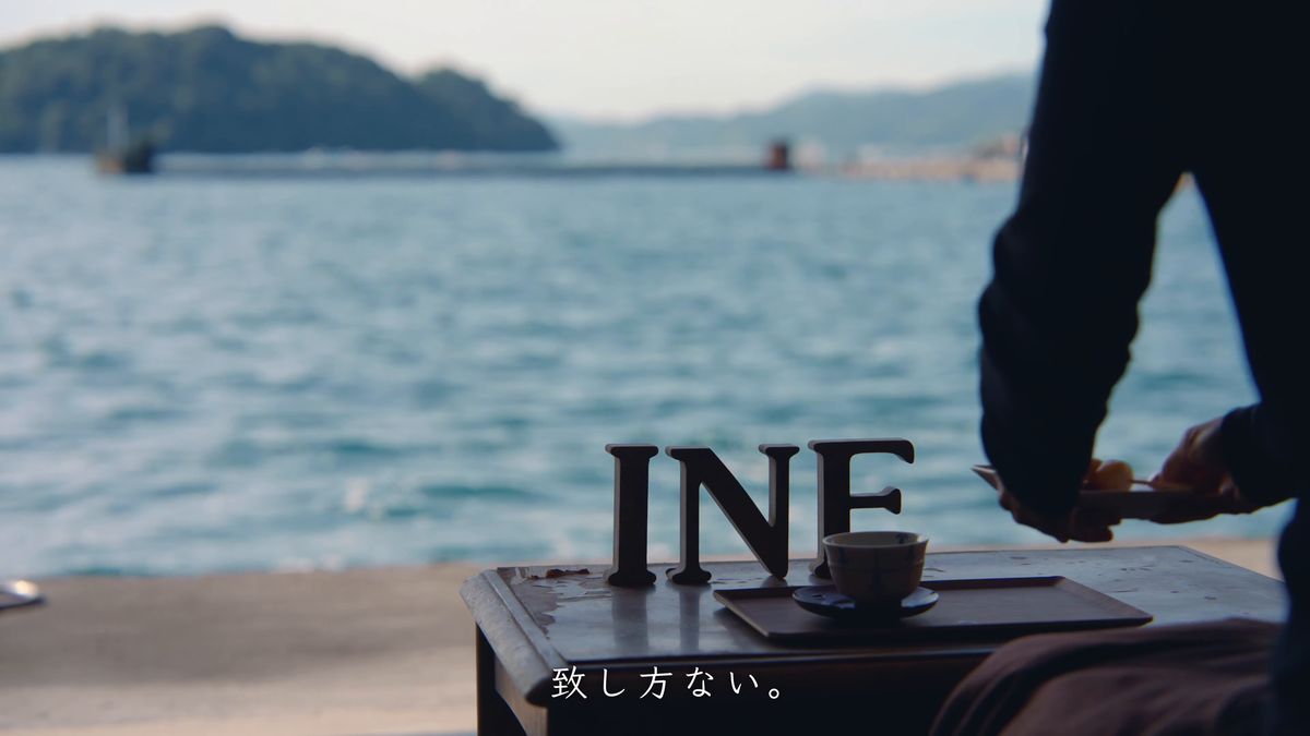 INE の木の文字と湯のみ、団子の皿を持つ手と青島