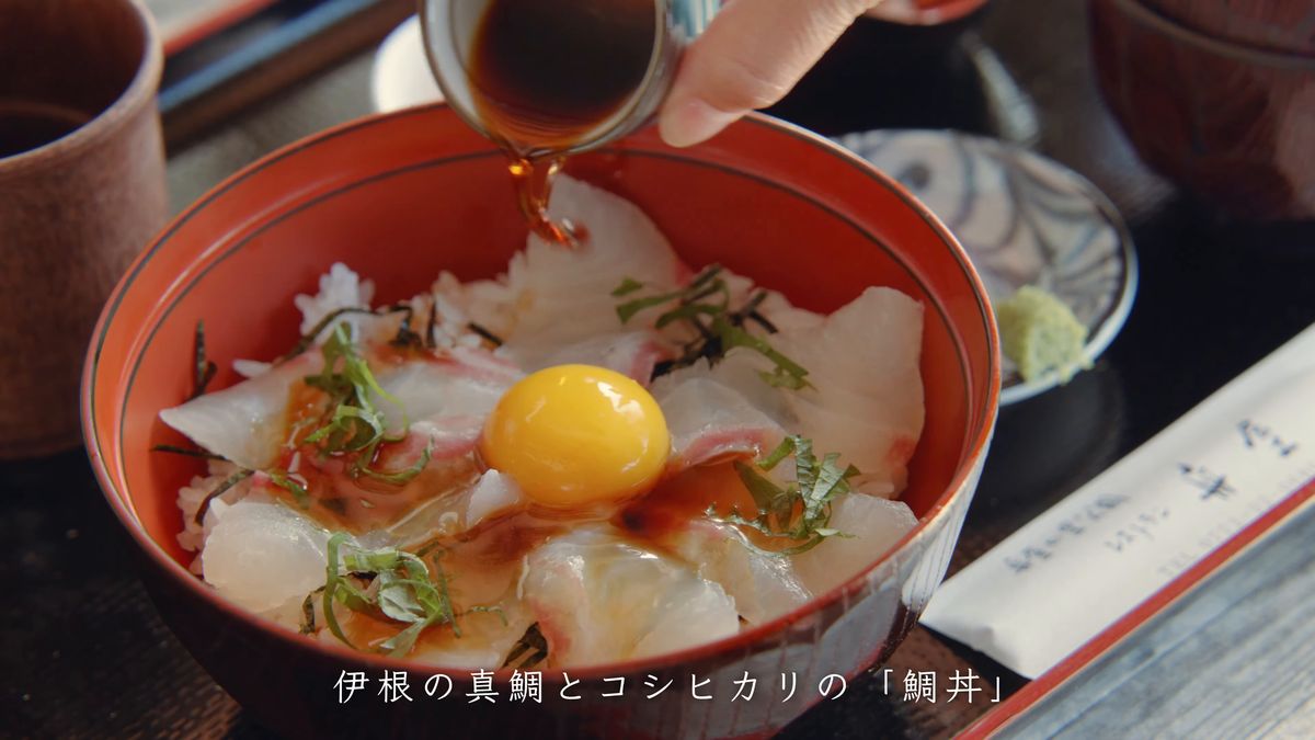 黄身をのせた鯛丼に醤油をかける手元