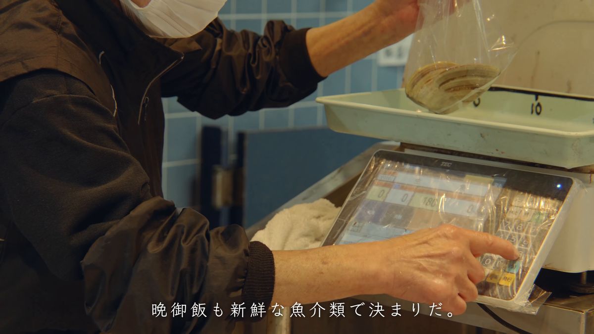 袋に入れた貝を量りにのせて会計する手元