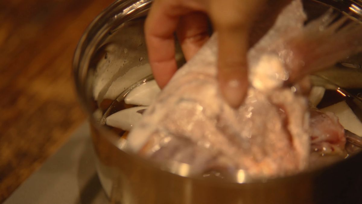 鍋に皮を剥いだカワハギを入れる手元