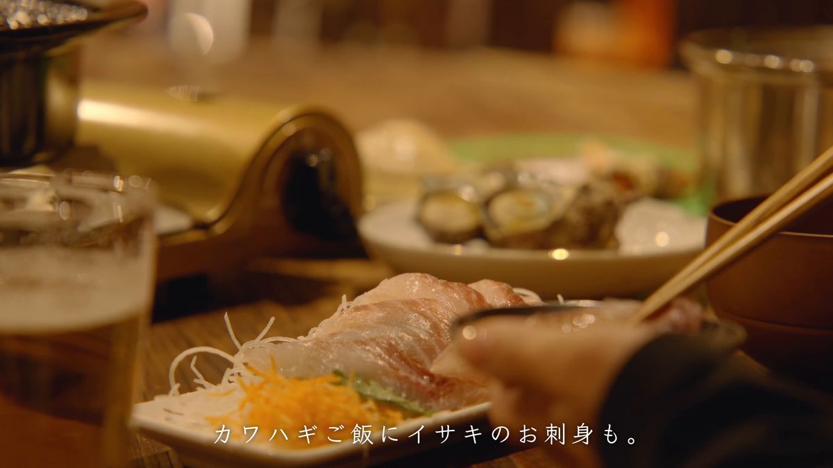 箸でつまんだイサキの刺身と、奥のグラス
