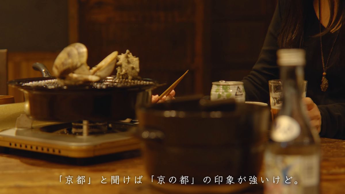 コンロの上の貝と鍋、瓶が並ぶ夜の食卓