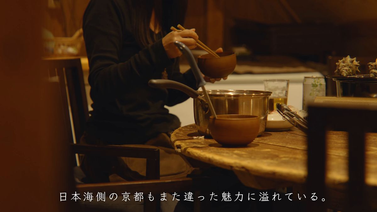 茶碗を手に、古民家の食卓でくつろぐ