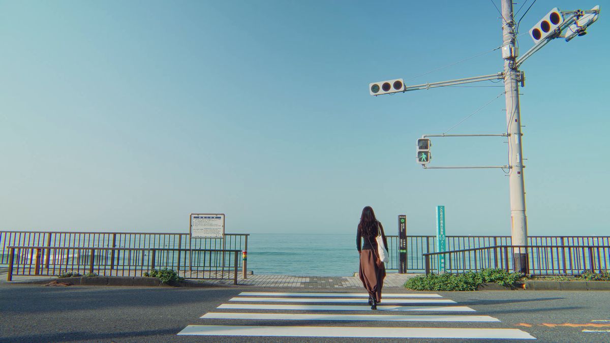 海を背にして横断歩道を渡る後ろ姿