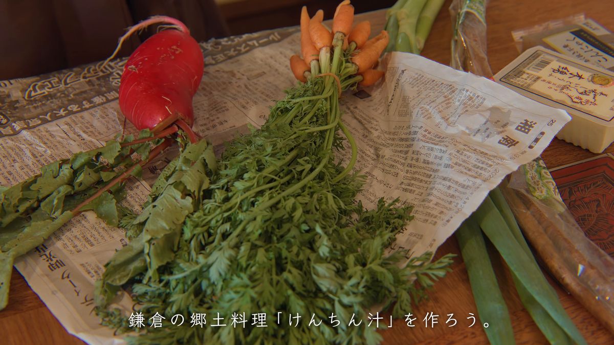 新聞紙の上に広げた赤大根、人参、長ねぎと豆腐