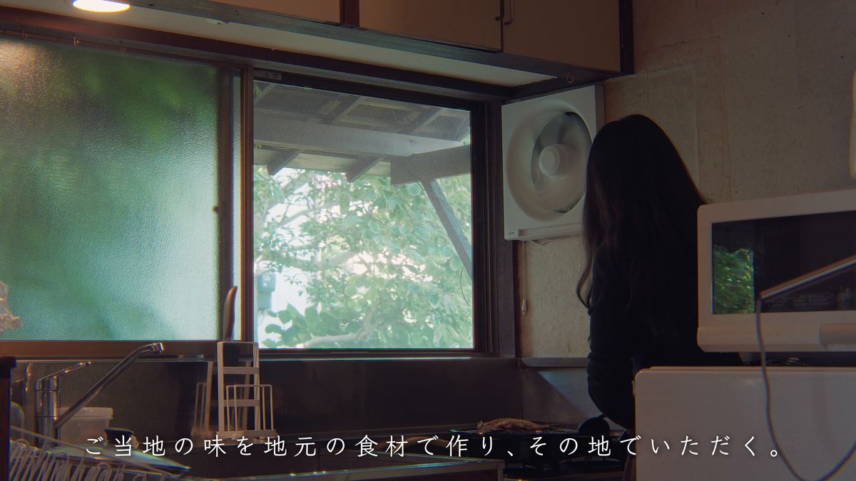 緑の見える台所の窓辺に立つ後ろ姿