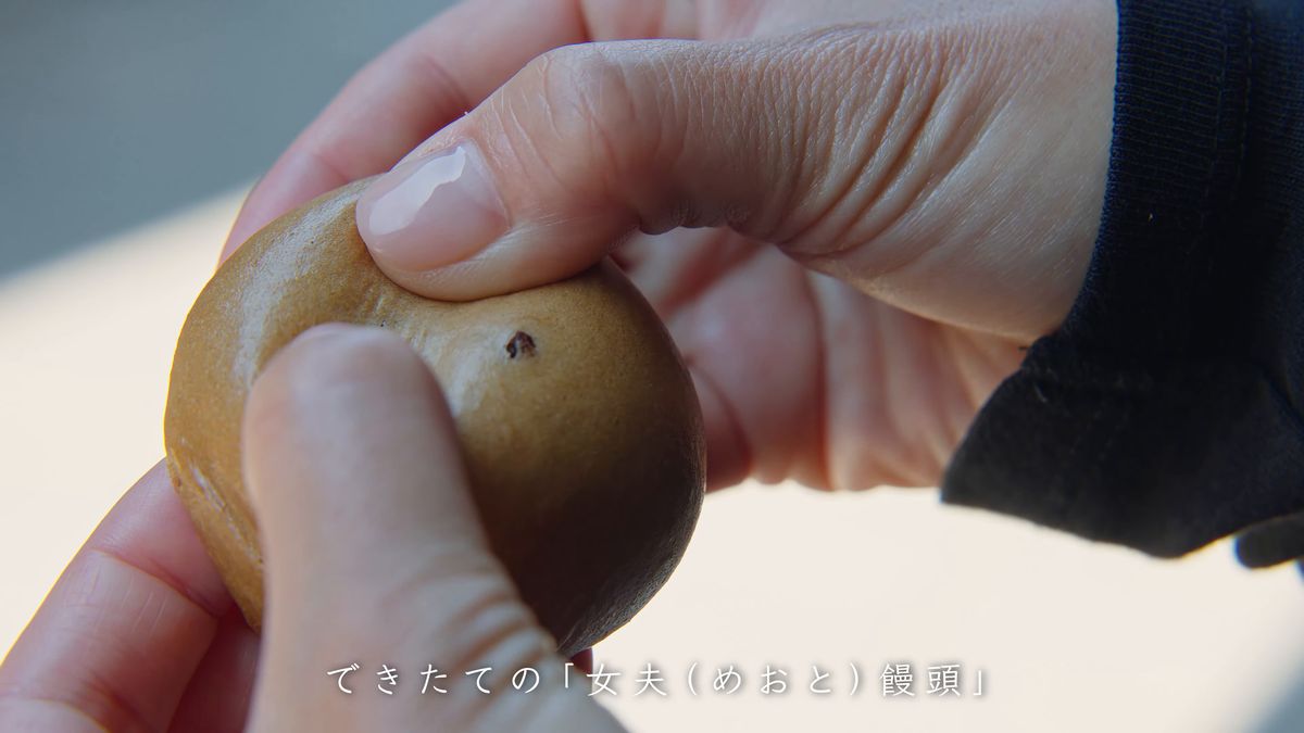 茶色い饅頭を手に持つ