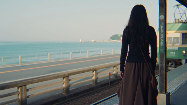 鎌倉高校前駅のホームに立つ後ろ姿と、海沿いを来る江ノ電