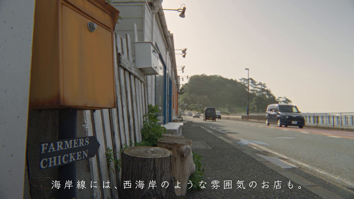 海沿いの道と、木の看板のかかる店の壁