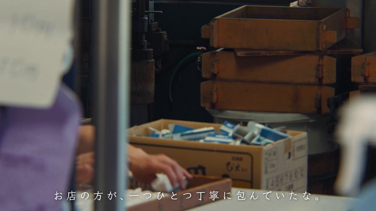 木箱の並ぶ店先で、最中を包む手元