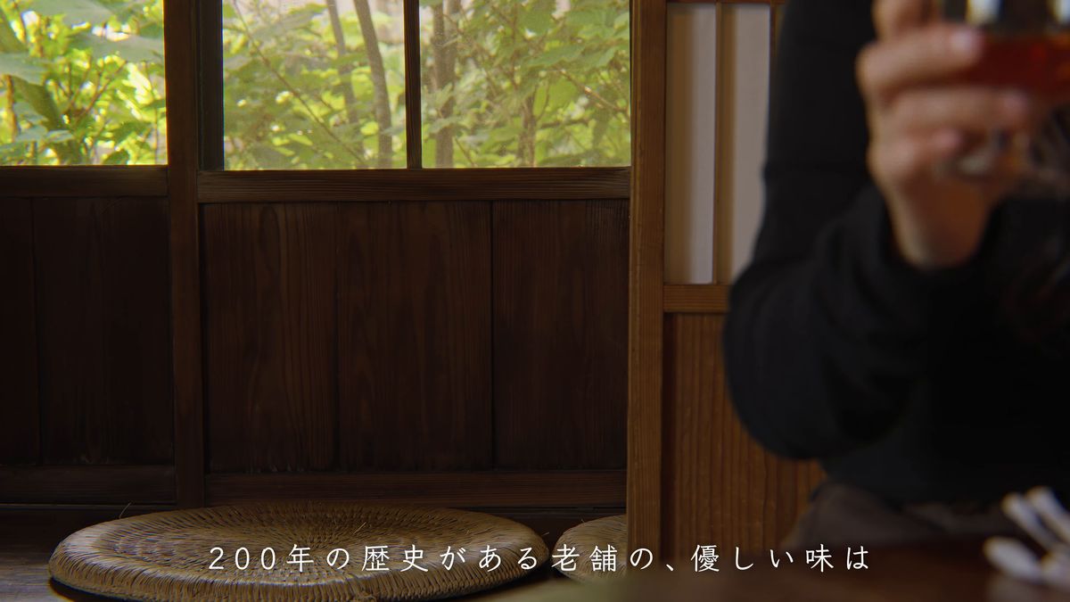 格子窓の向こうの緑と、グラスを持つ手