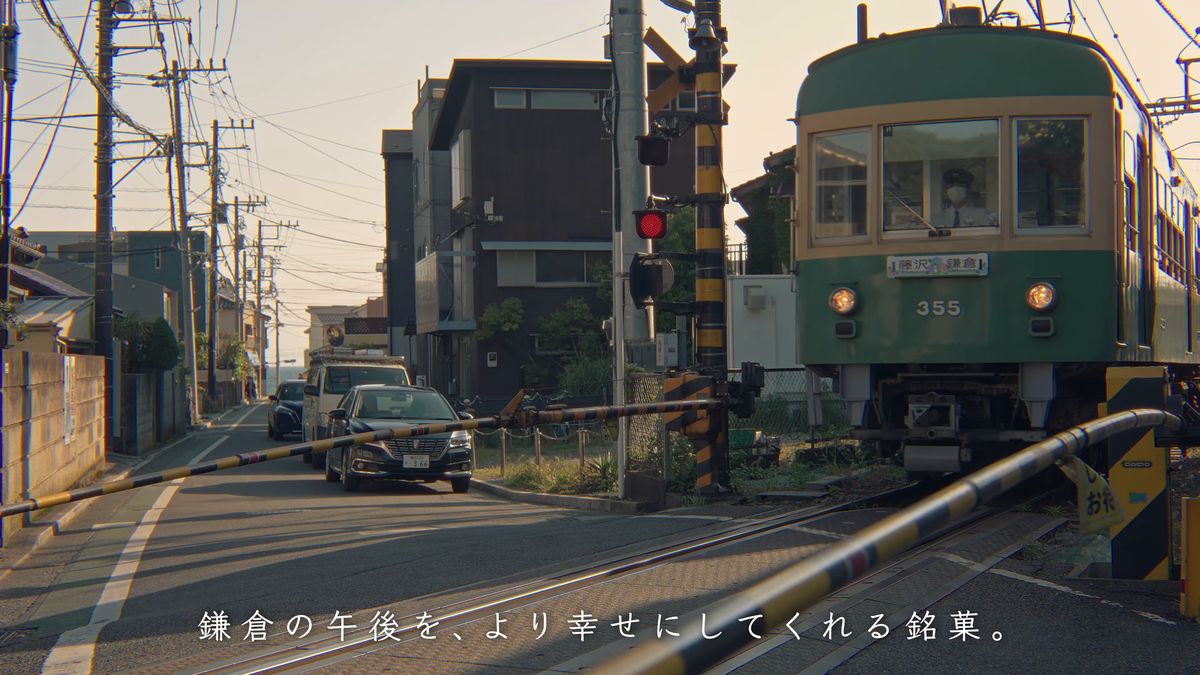 住宅街の踏切の前を通る江ノ電