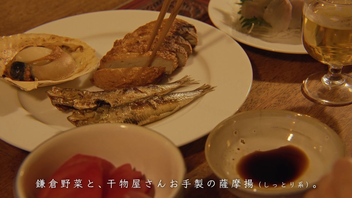 薩摩揚げを箸で取る、焼いた貝とイワシの皿