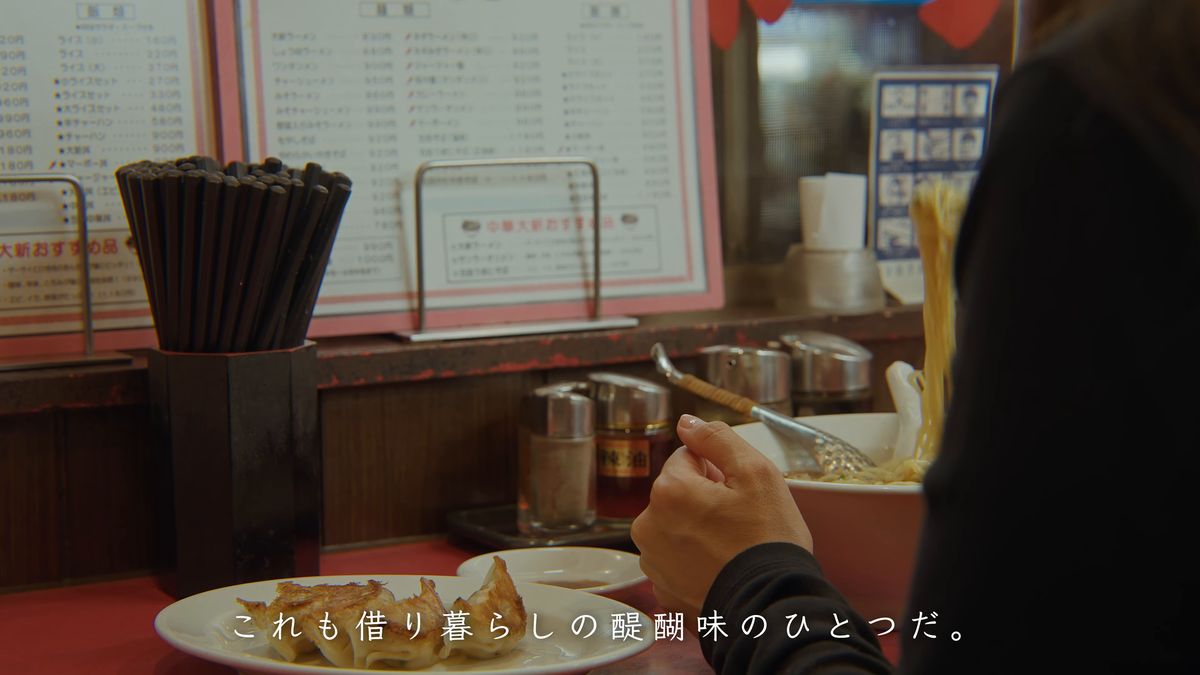カウンターで食べる後ろ姿と壁の品書き