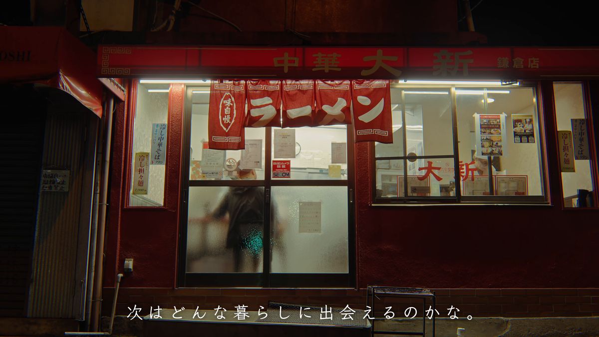 明かりの灯る店の入り口から出てくる後ろ姿