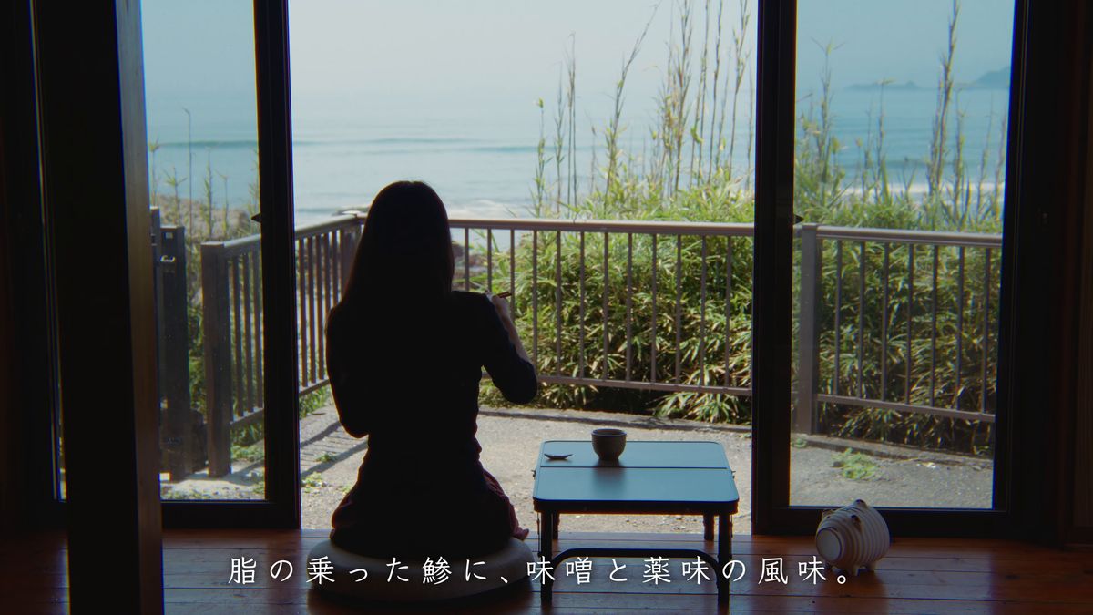 海を見ながら小さな机の前に座る後ろ姿