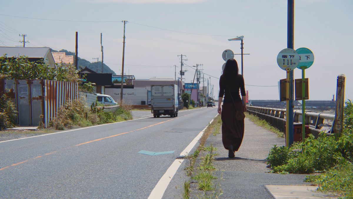 海沿いの道を歩く後ろ姿