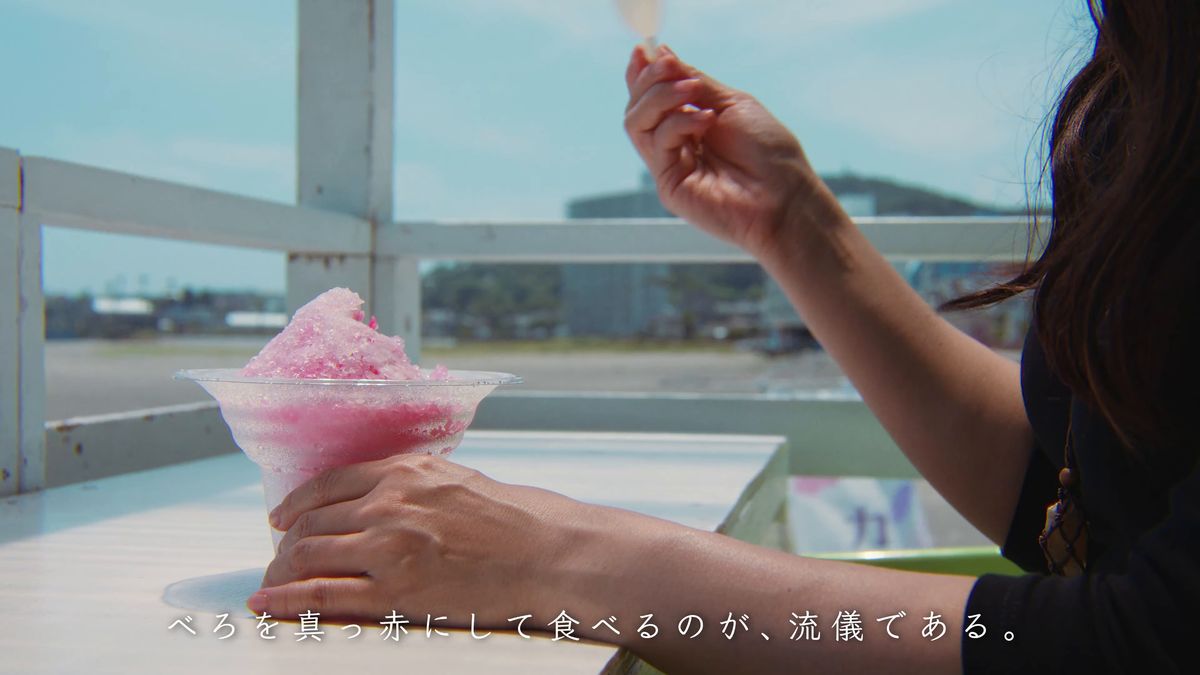 赤いシロップのかき氷を手に持つ
