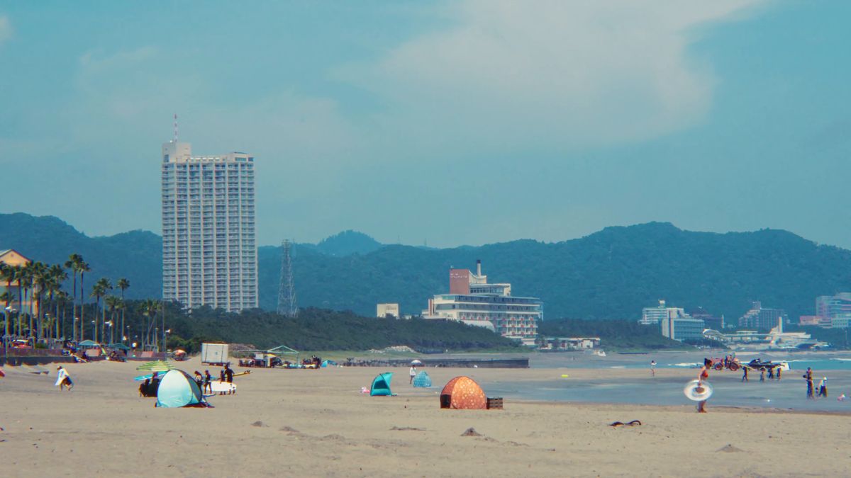 テントの並ぶ砂浜と高層ホテル