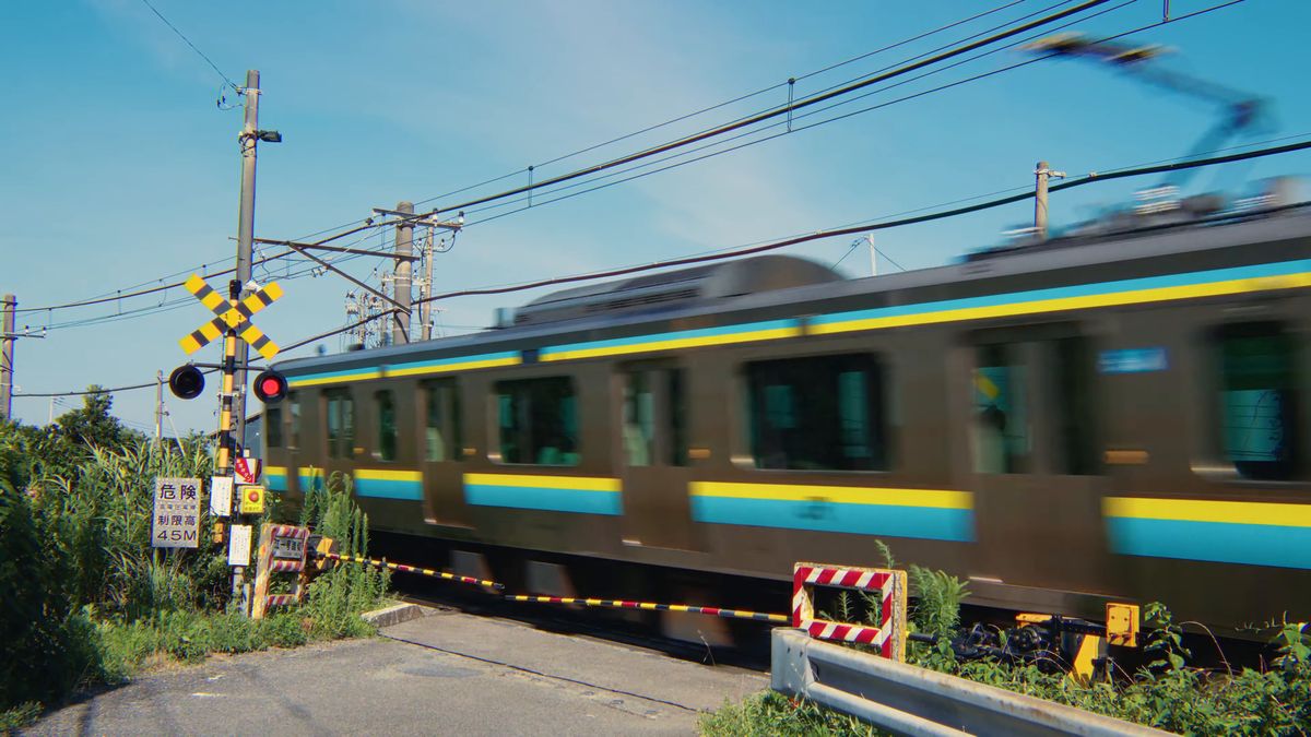 踏切を通過する青と黄色の帯の電車