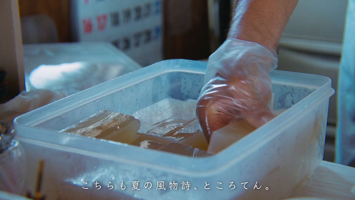 水を張った容器からところてんを取り出す店の人の手元