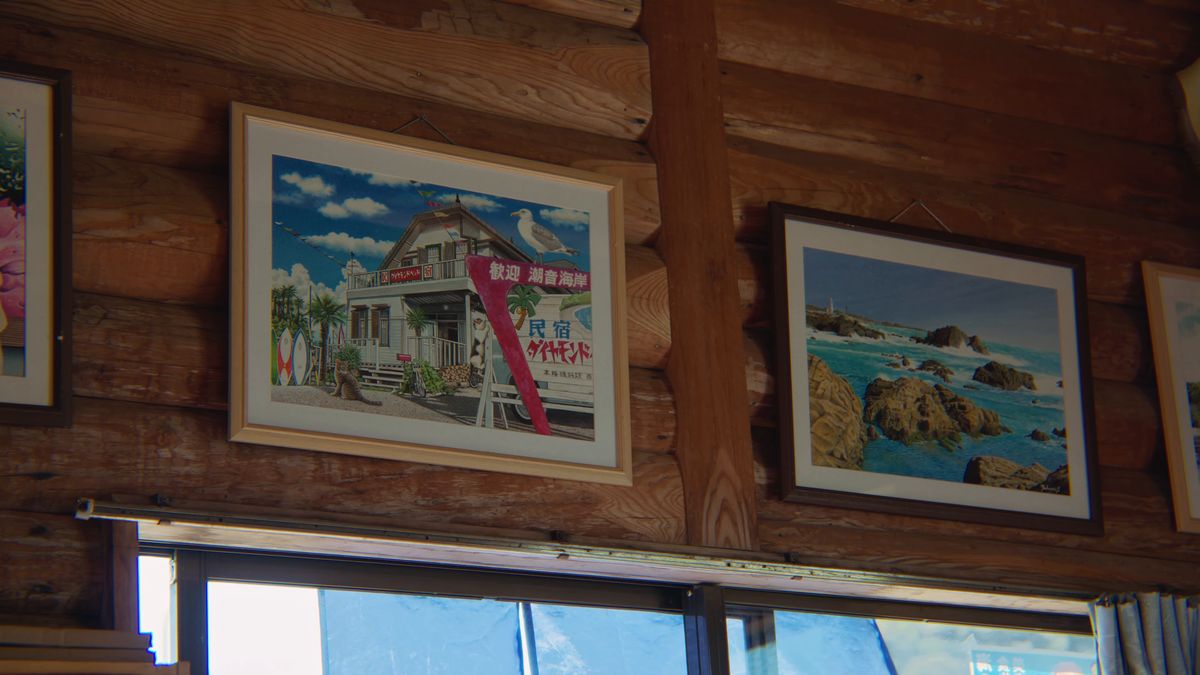 壁に飾られた海辺の建物の絵と岩場の写真