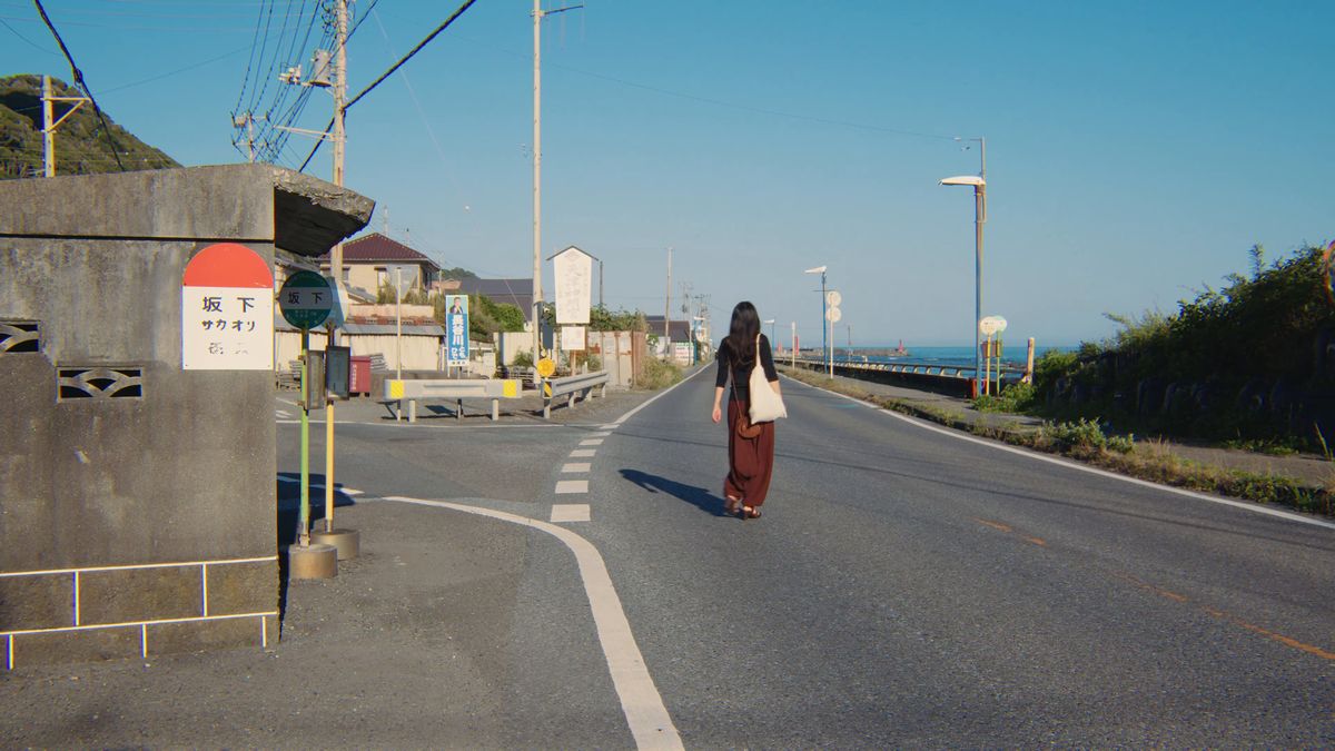 バス停の角から、海へ続く道を歩く後ろ姿