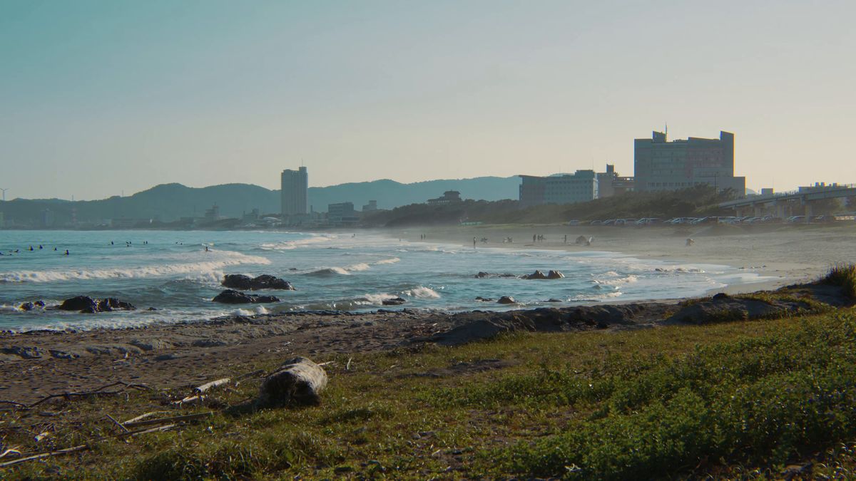 夕方の浜に砕ける波と遠くのホテル