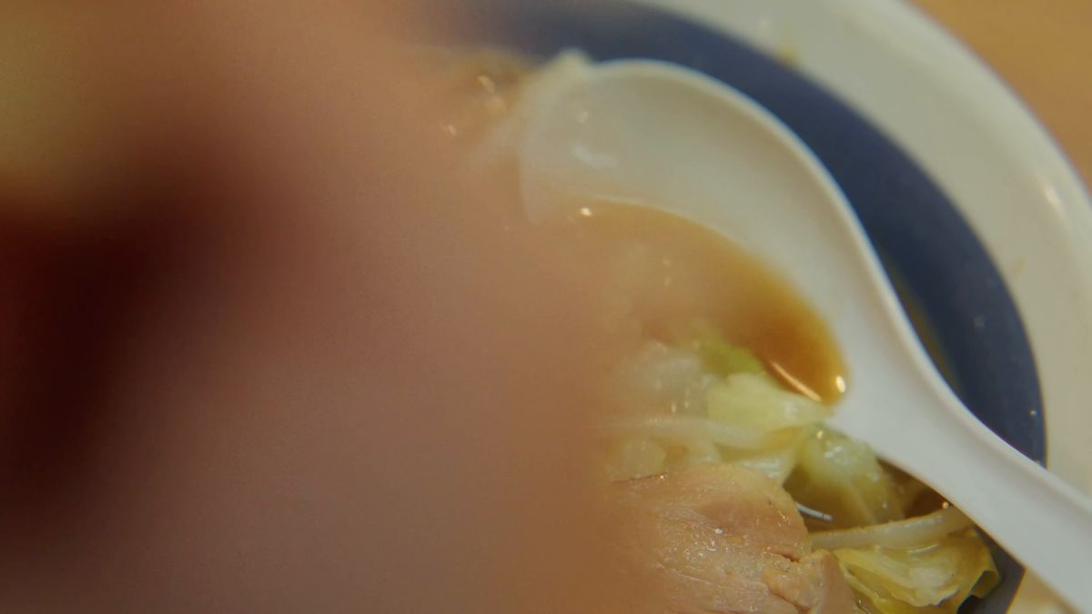 レンゲとスープの前をよぎる手