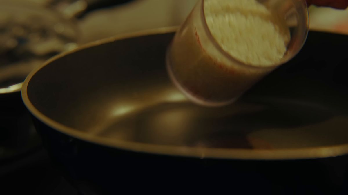 計量カップの米を鍋に入れる
