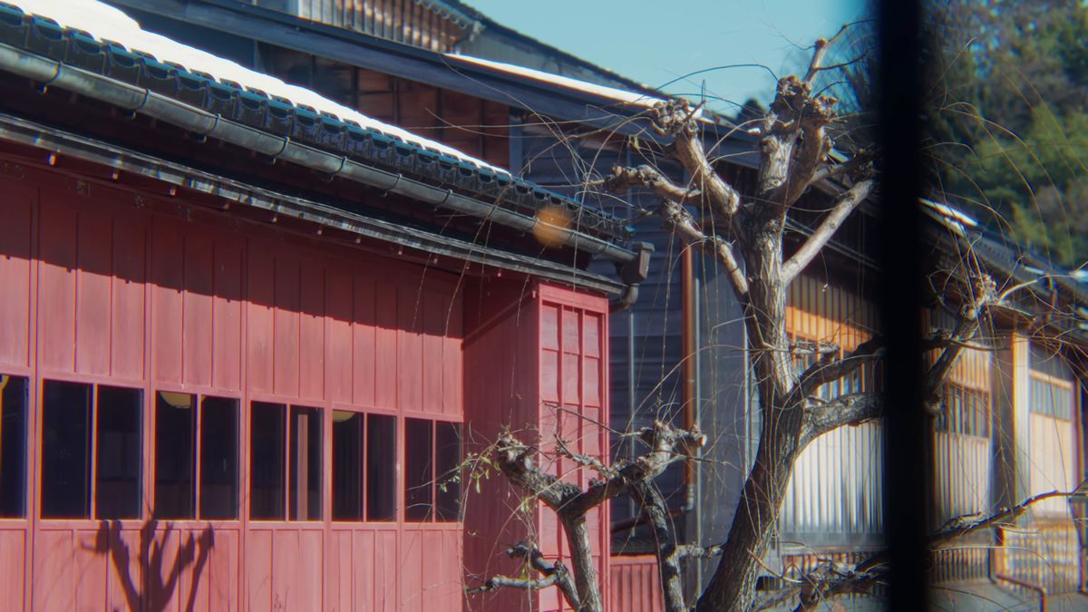 屋根に雪の残る紅殻色の茶屋と、刈り込まれた木