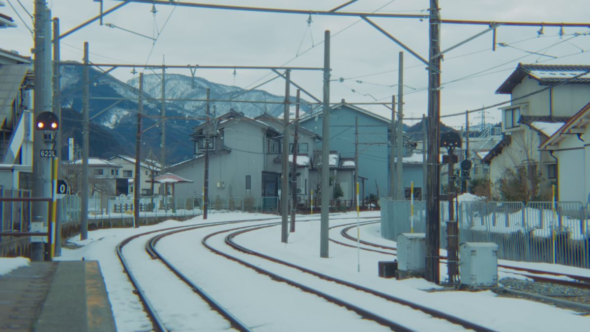 雪の残る線路のカーブと山並み